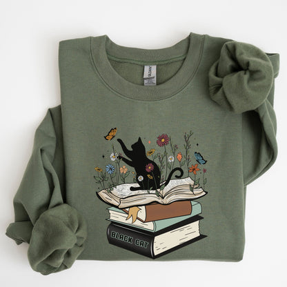 Green sweatshirt with a graphic of a black cat on books and flowers on a white background
