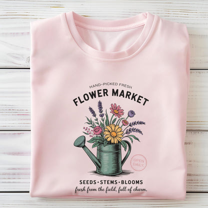 Pink t-shirt with floral design and text on a wooden surface