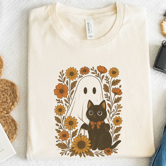 Natural t-shirt with a black cat and ghost design surrounded by flowers on a light background