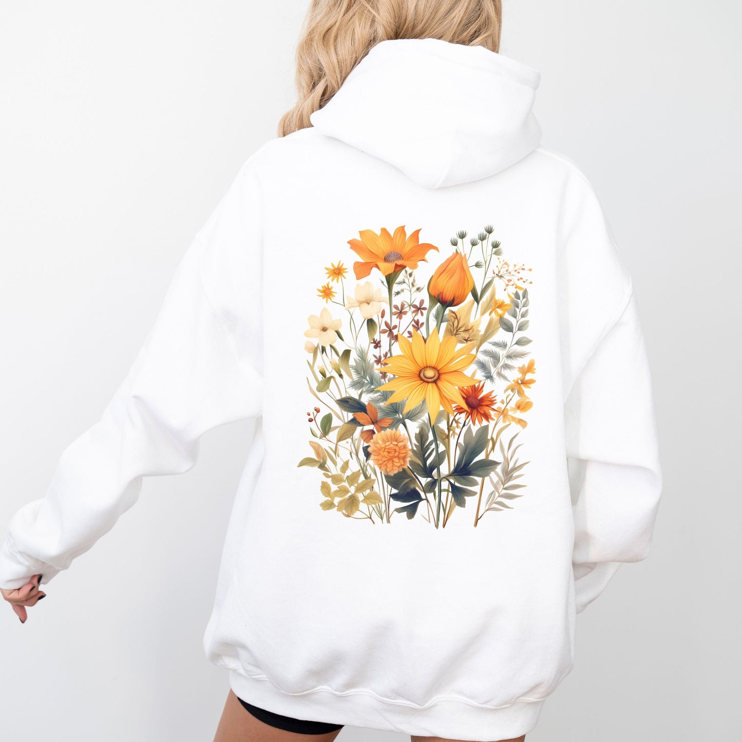 A person shown from the back wearing a white pullover hoodie with a large colorful floral print on the back, photographed against a clean white studio background.