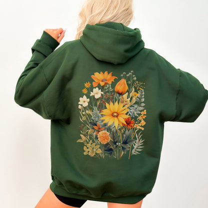 A person shown from the back wearing an oversized dark green hoodie with a large colorful floral print on the back, photographed against a plain light background.