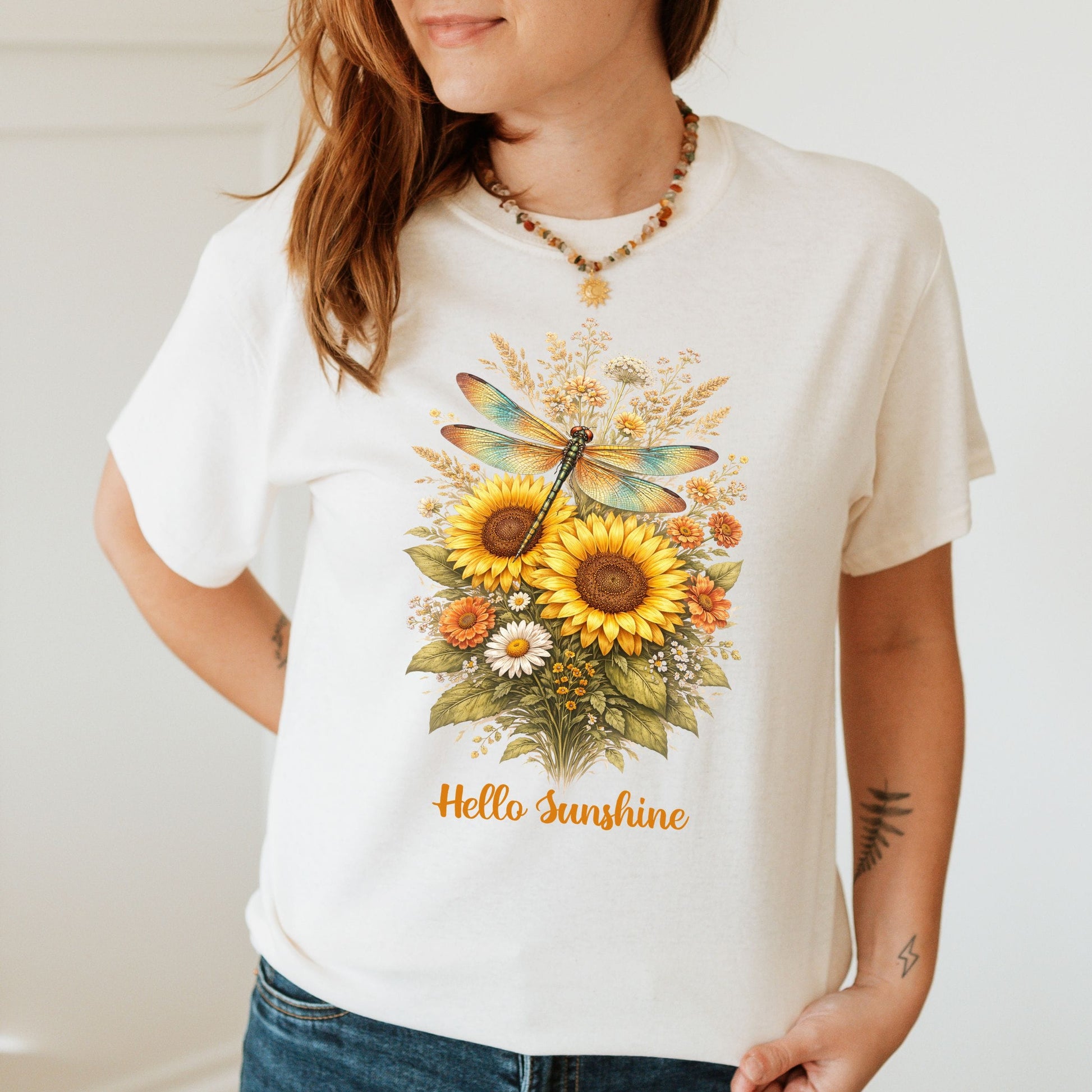 Person wearing a white t-shirt with a floral design and 'Hello Sunshine' text.