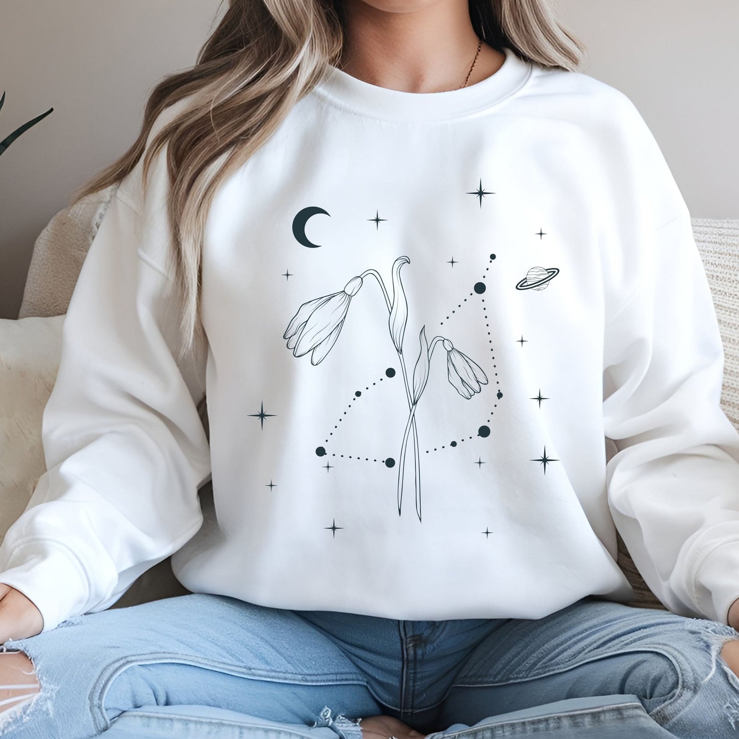 Person wearing a white sweatshirt with celestial design