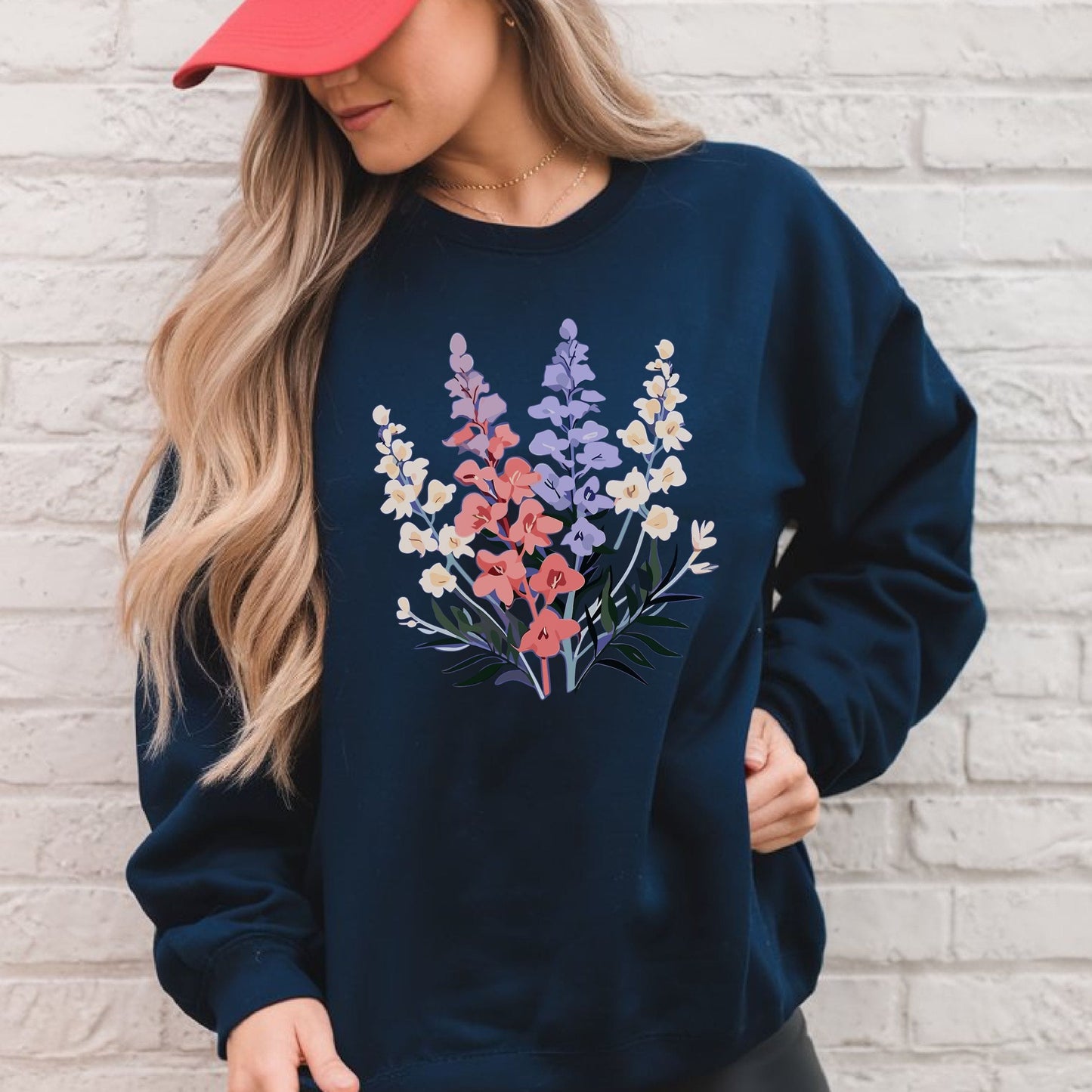 Person wearing a navy sweatshirt with floral design against a light brick wall.