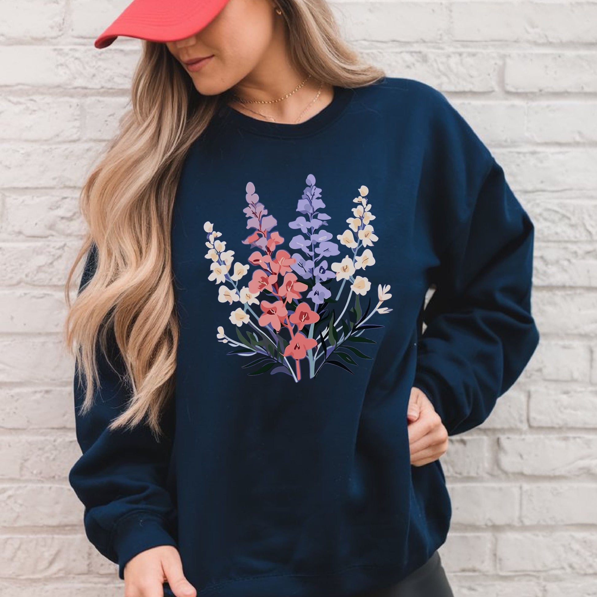 Person wearing a navy sweatshirt with floral design against a light brick wall.