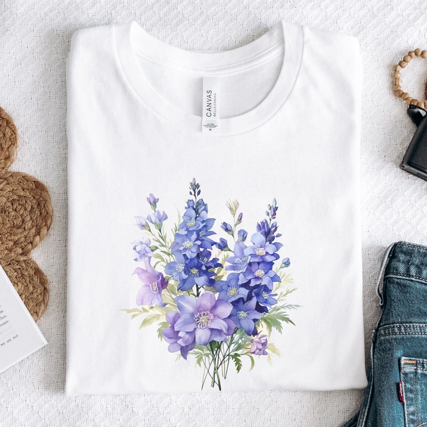White t-shirt with a blue floral design on a light gray surface.