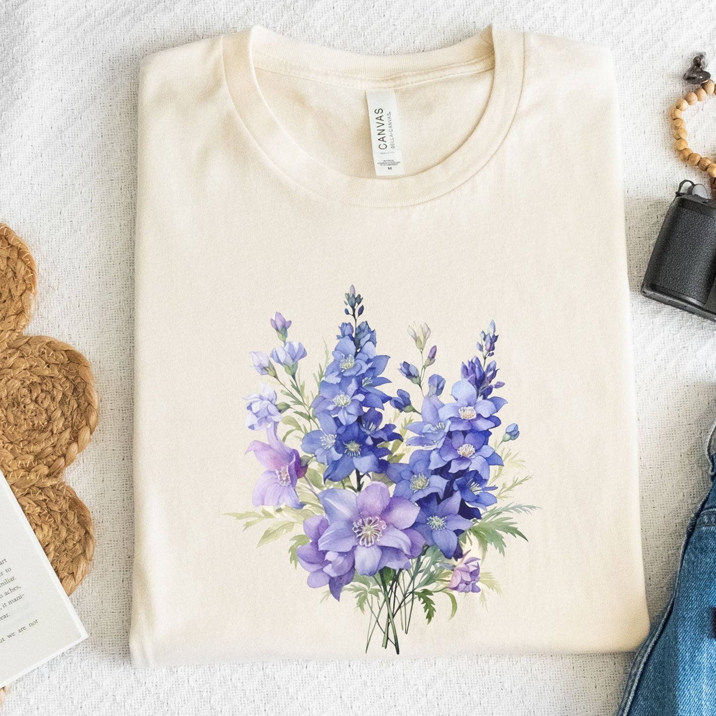 Beige t-shirt with a purple floral design on a textured surface.