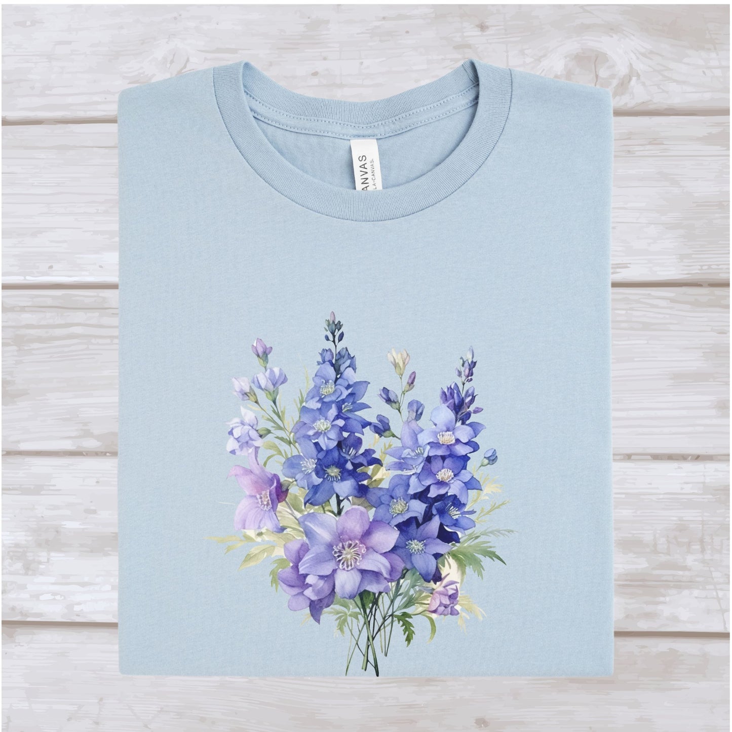 Light blue t-shirt with a purple floral design on a wooden surface