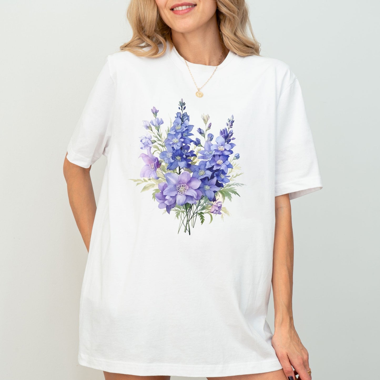 Woman wearing a white t-shirt with a purple floral design on a plain background