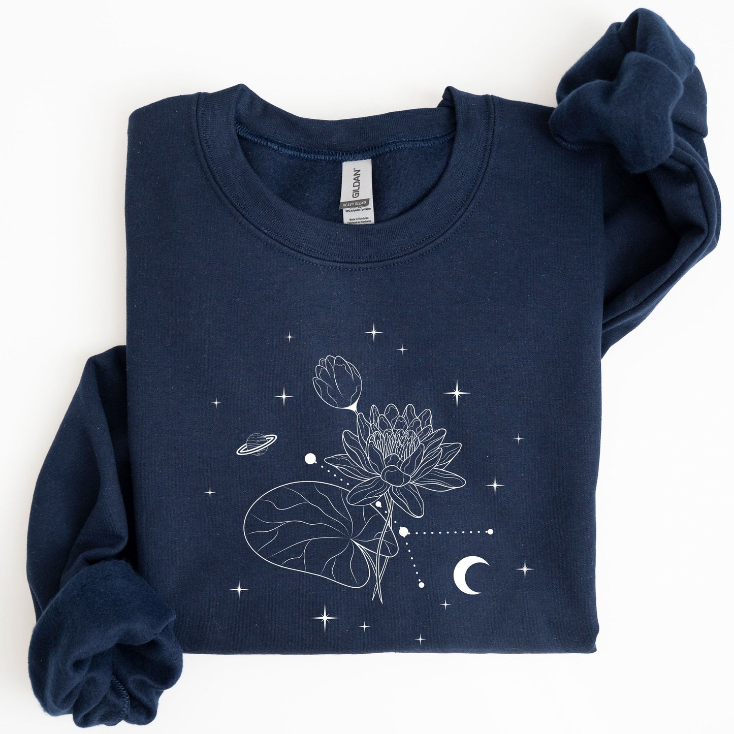 Folded navy blue sweatshirt with white floral and celestial design on a white background