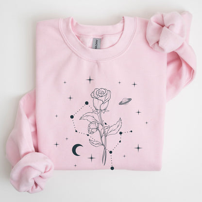 Pink sweatshirt with black floral and moon design on a light gray background