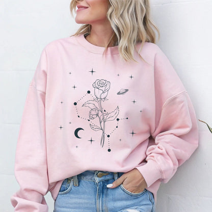 Person wearing a pink sweatshirt with floral and celestial design against a white background