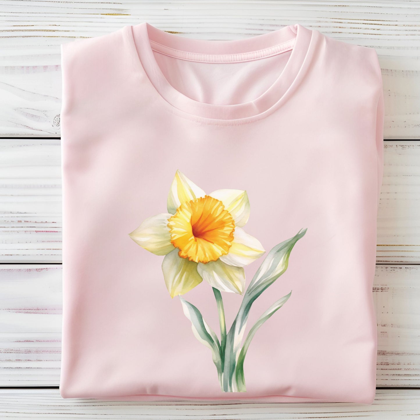 Pink t-shirt with a yellow flower design on a wooden surface