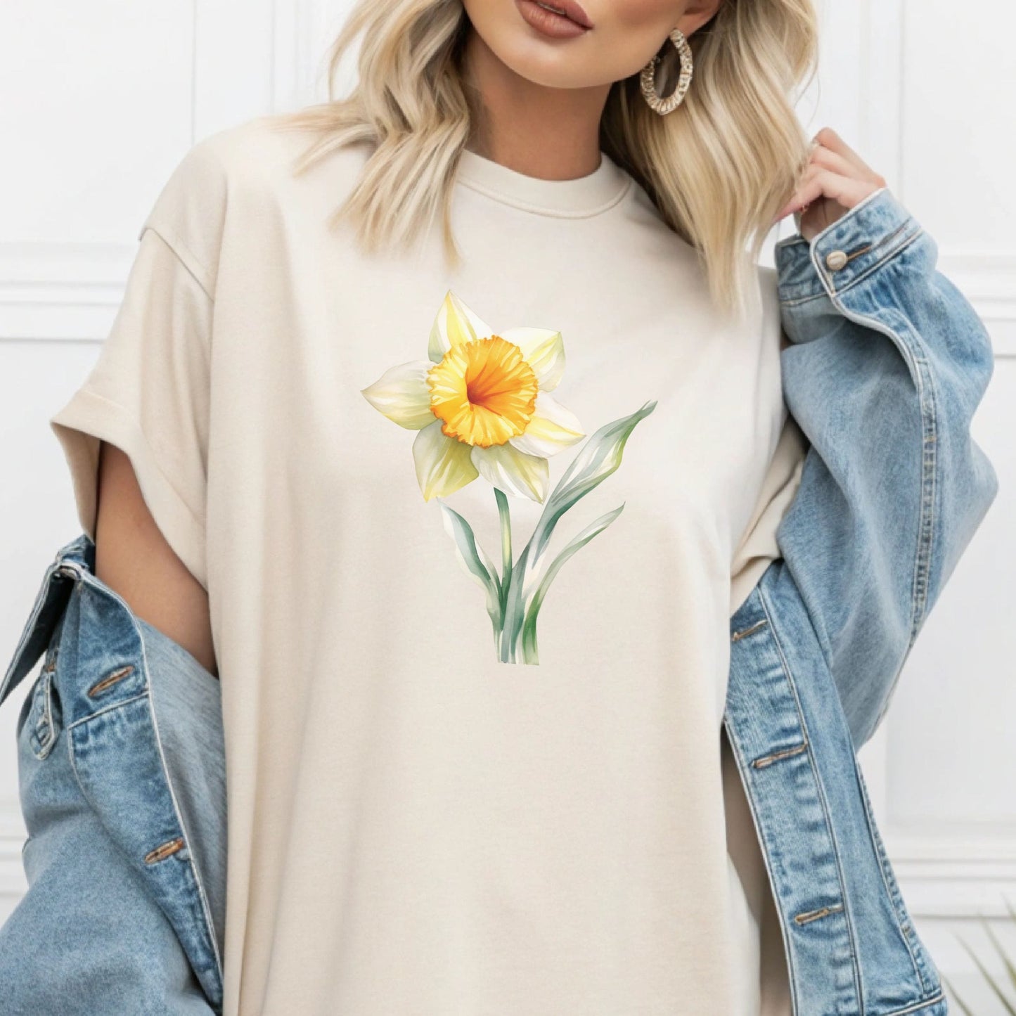 Person wearing a white t-shirt with a yellow flower design, paired with a denim jacket.