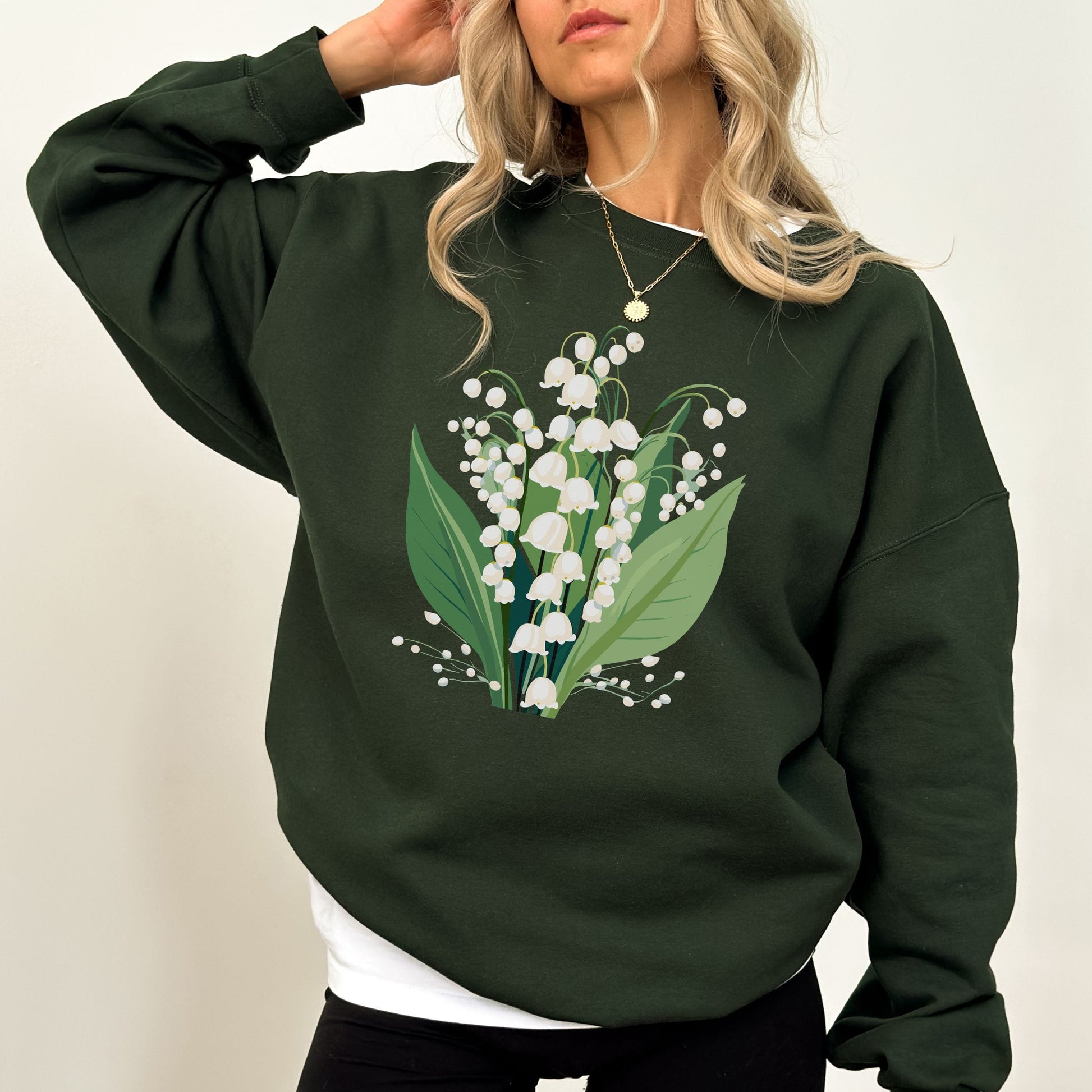 Person wearing a dark green sweatshirt with a floral design on a plain background