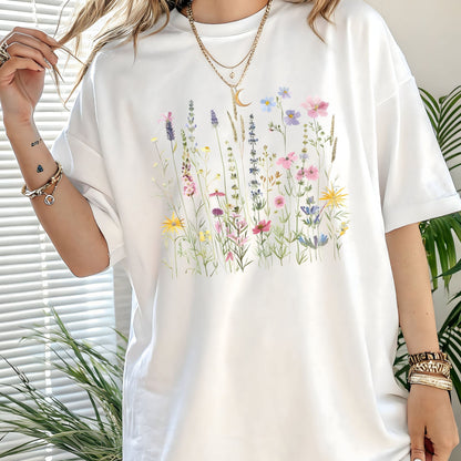 White t-shirt with floral design worn by a person, with plants in the background