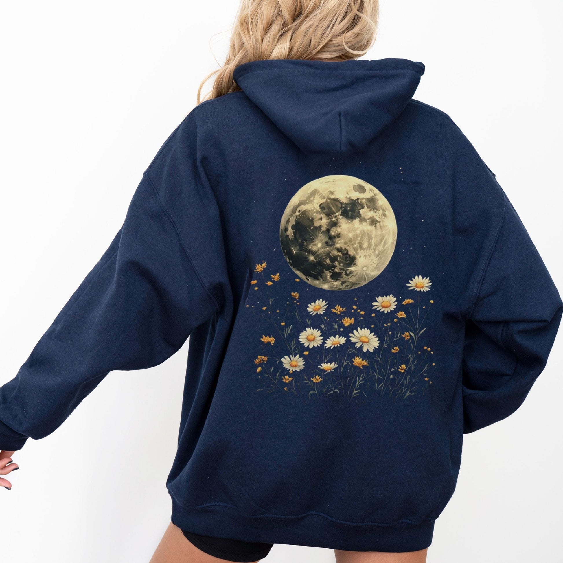 Navy blue hoodie with a moon and floral design on the back, worn by a person.