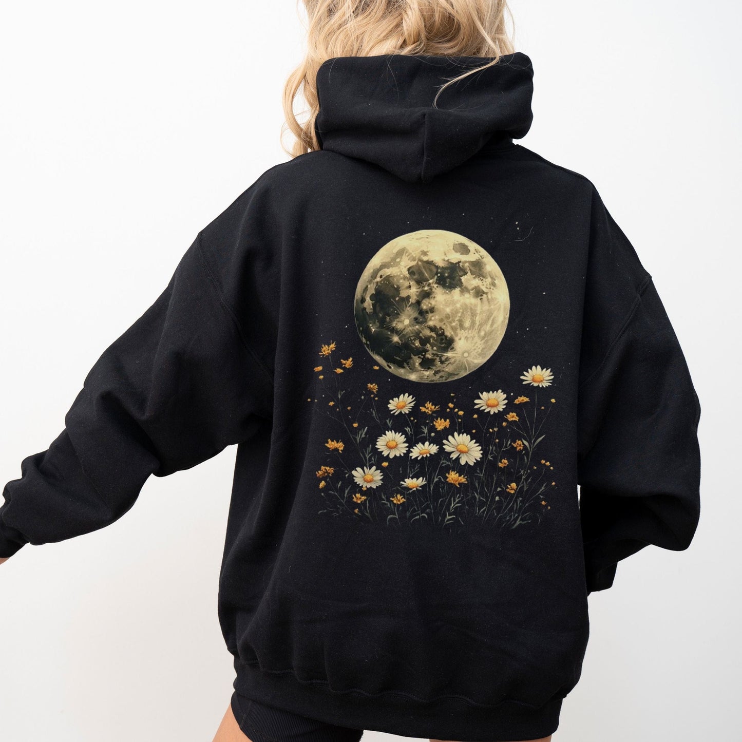 Black hoodie with a moon and floral design on the back, worn by a person.