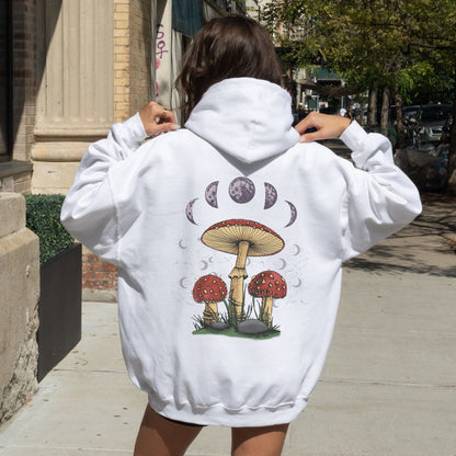Person wearing a white hoodie with mushroom design on the back, standing outdoors.