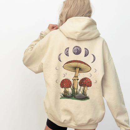 Beige hoodie with mushroom and moon phase design on the back, worn by a person.