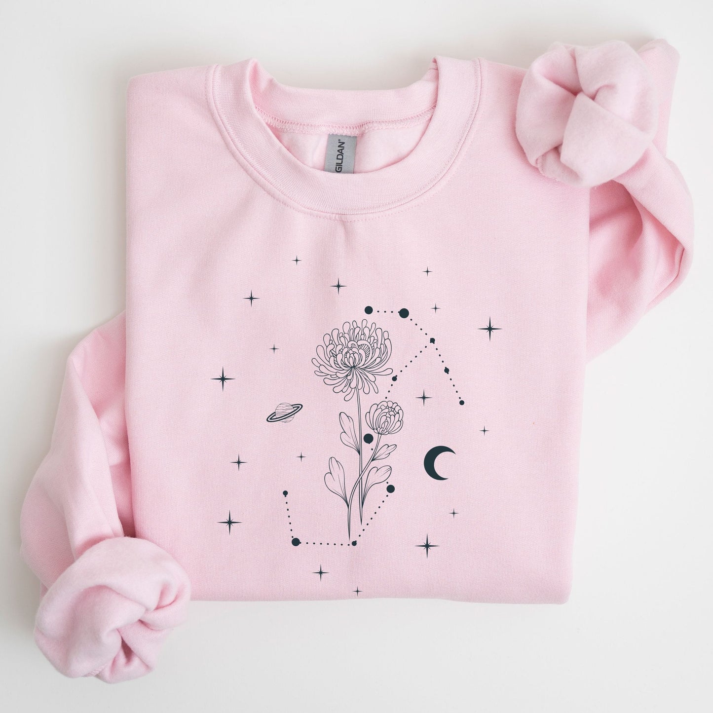 Pink sweatshirt with black floral and celestial design on a light gray background