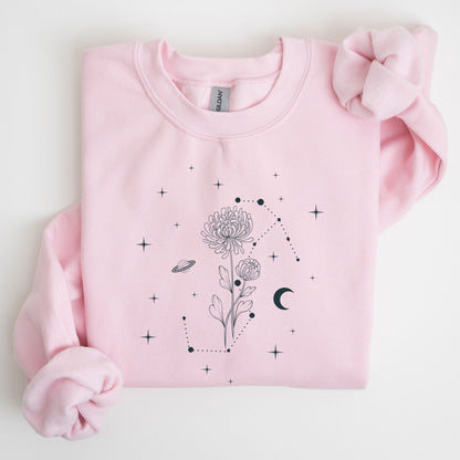 Pink sweatshirt with black floral and celestial design on a light gray background