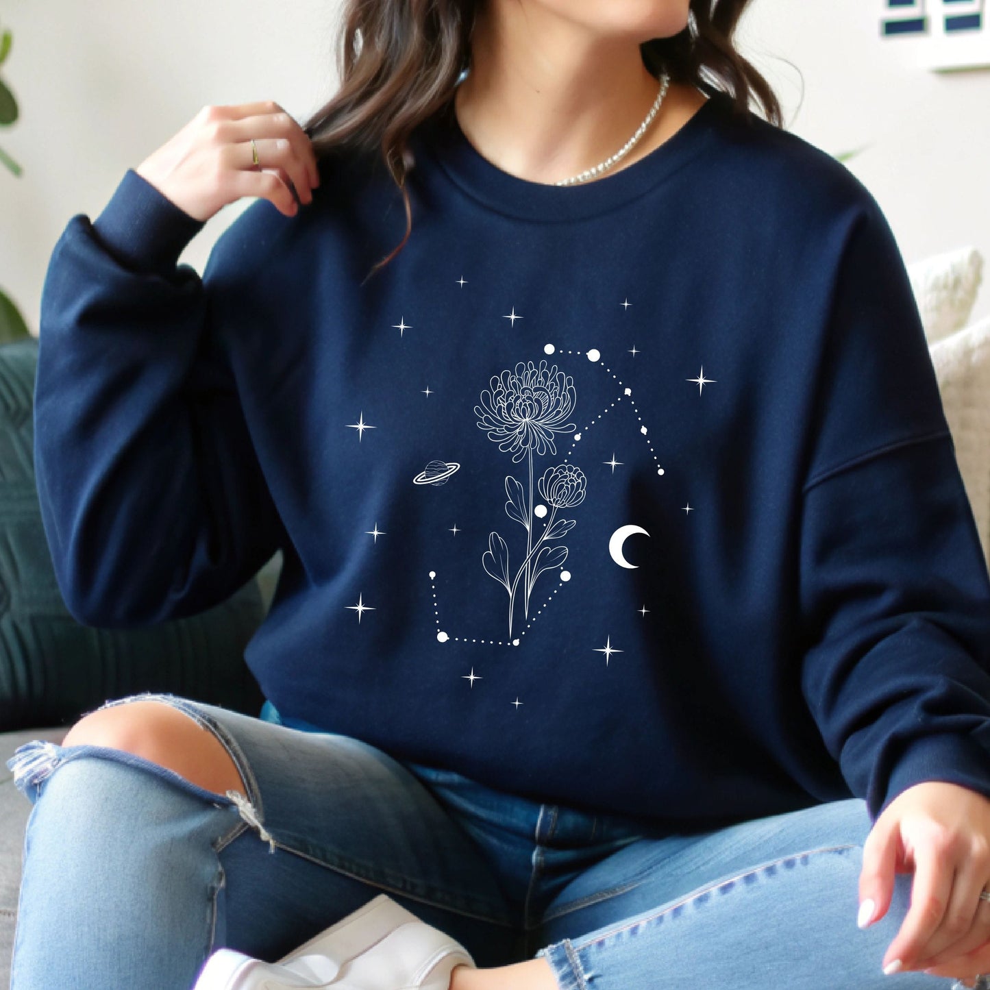 Person wearing a navy blue sweatshirt with celestial design
