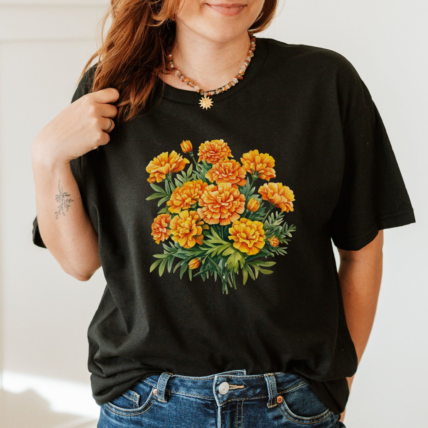 Person wearing a black t-shirt with a floral design on a plain background