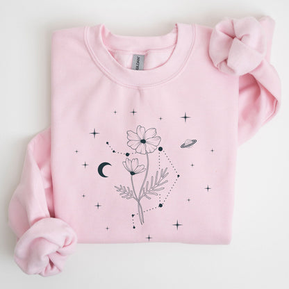 Pink sweatshirt with floral and celestial design on a light gray background