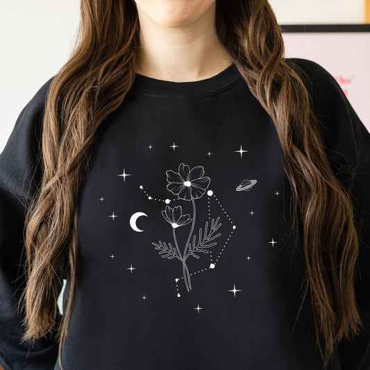 Person wearing a black sweatshirt with white floral and celestial design