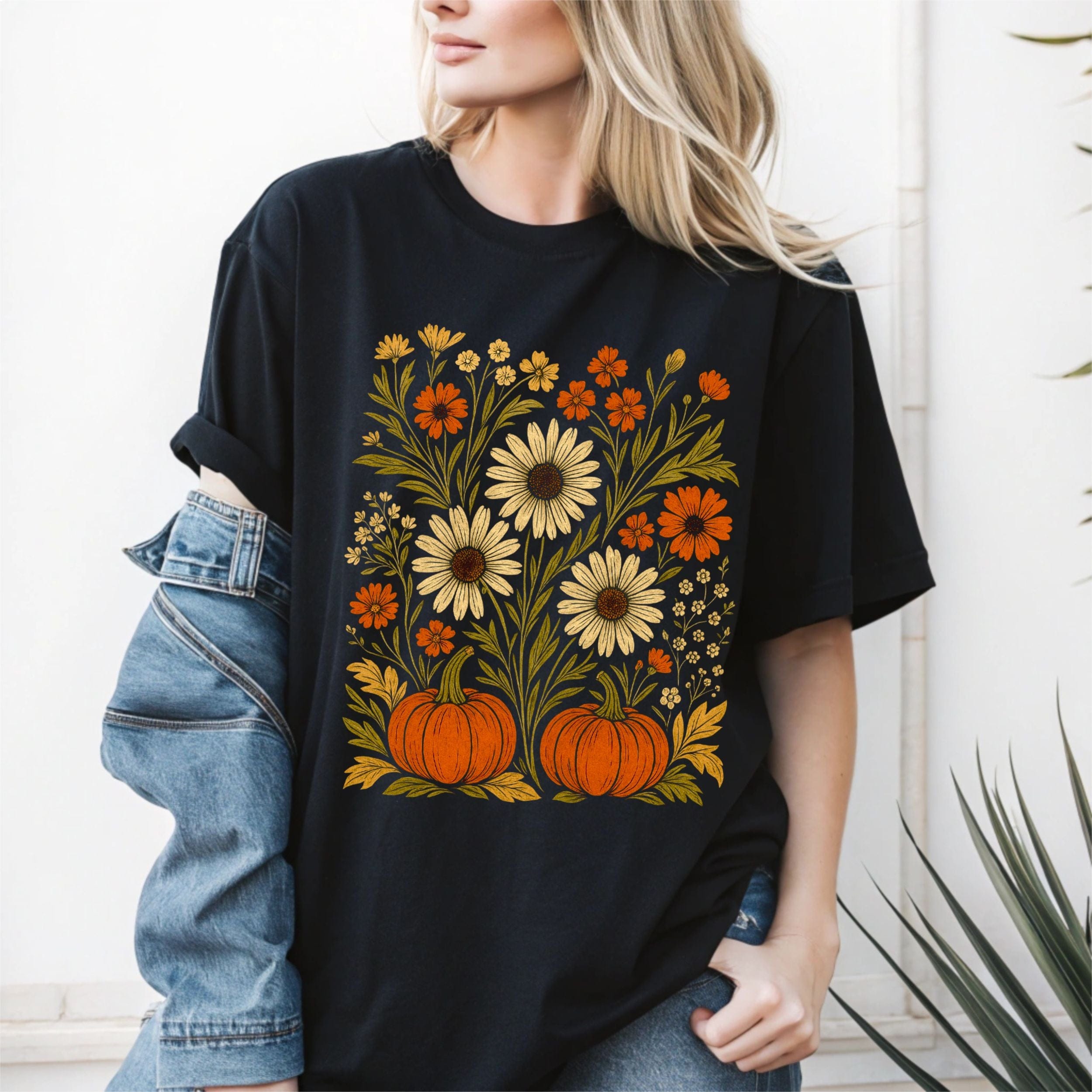 Person wearing a black t-shirt with floral and pumpkin design