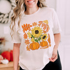 Person wearing a white t-shirt with autumn-themed design featuring sunflowers and pumpkins.