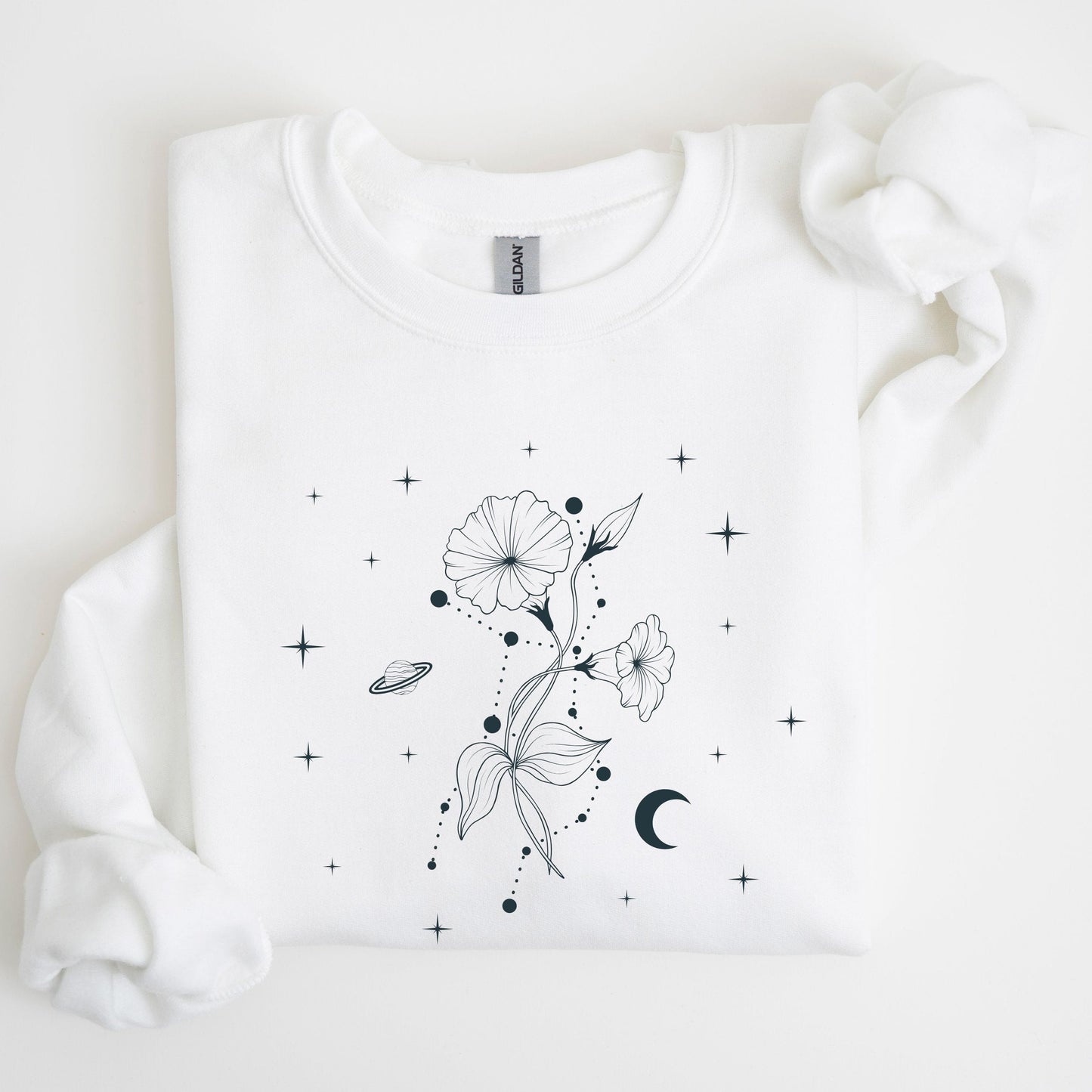 Folded white sweatshirt with a celestial floral design on a white background