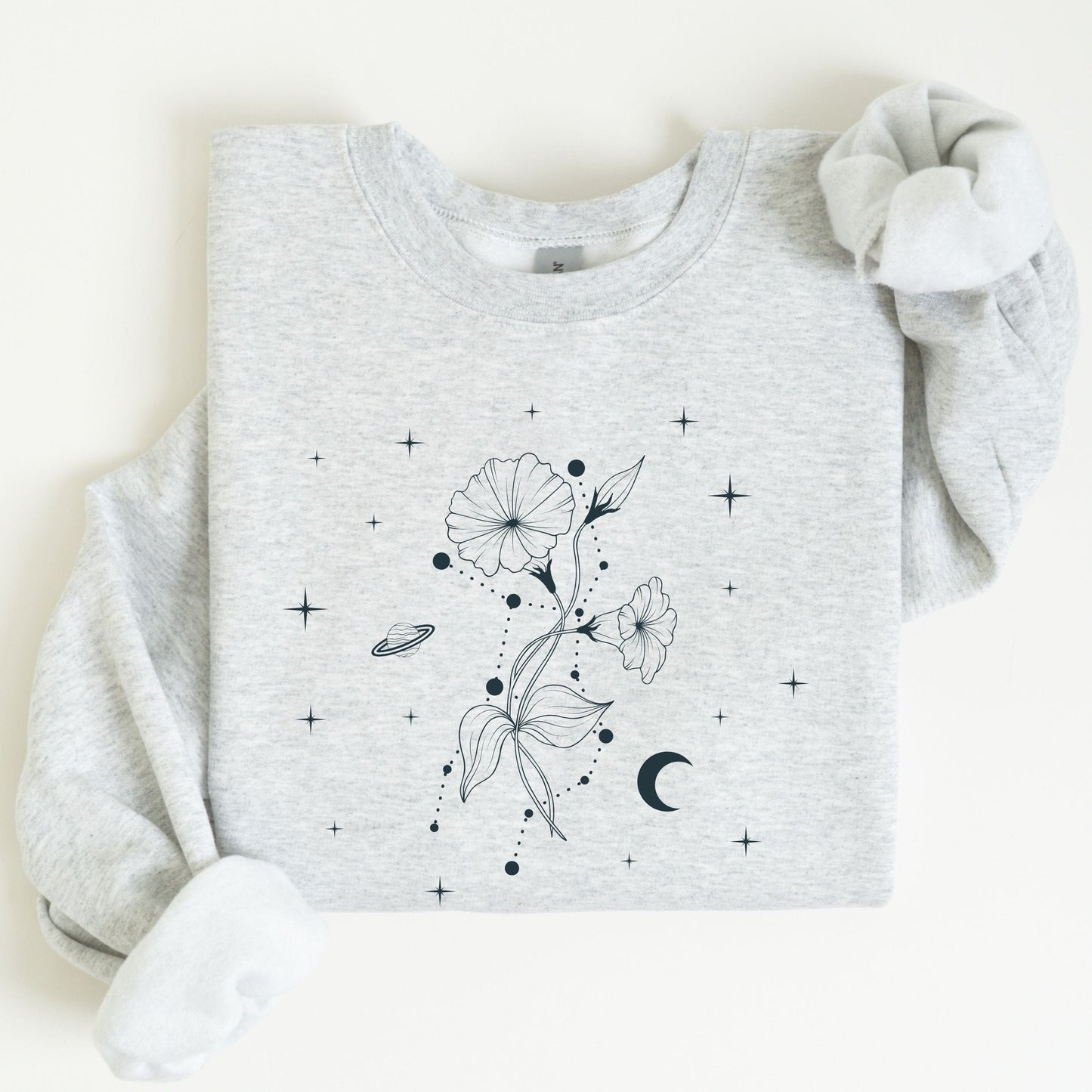 Folded grey sweatshirt with a celestial floral design on a white background