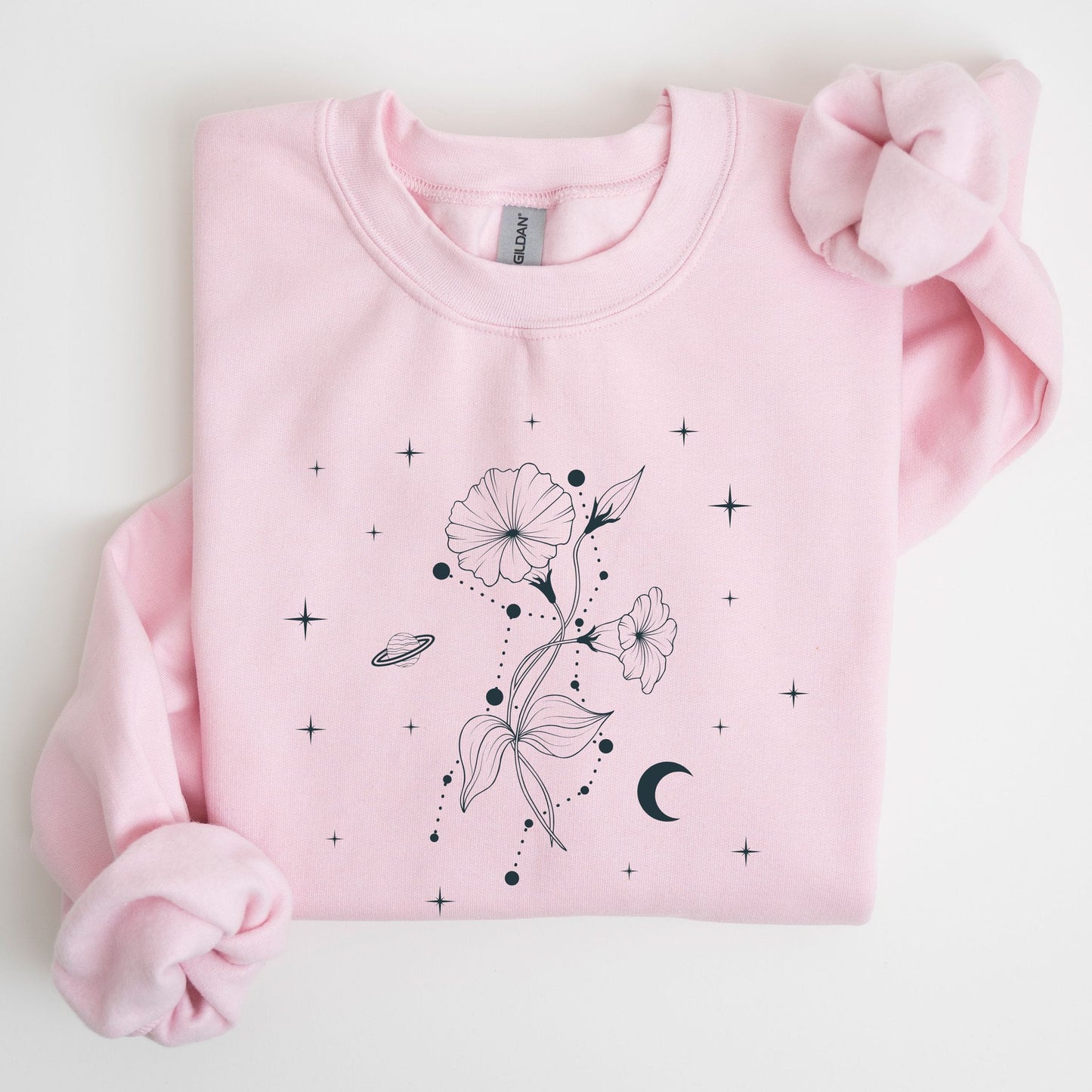 Folded pink sweatshirt with a celestial floral design on a white background