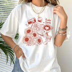 White t-shirt with red graphic design featuring sunflowers, a camera, and text, worn by a person.