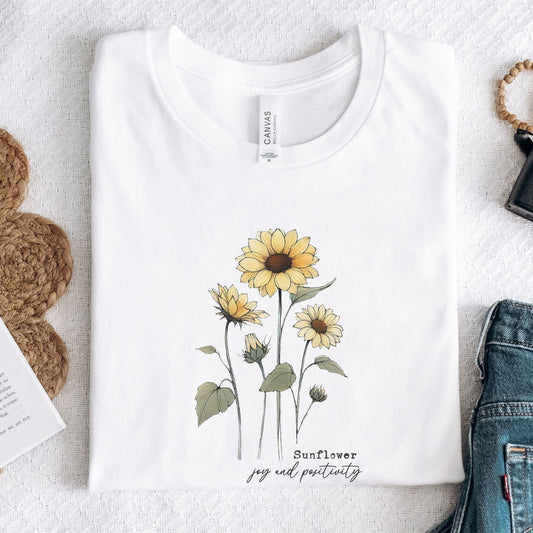 White t-shirt with sunflower design and text on a light gray surface.