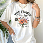 Person wearing a white t-shirt with 'The Flower Market' design.