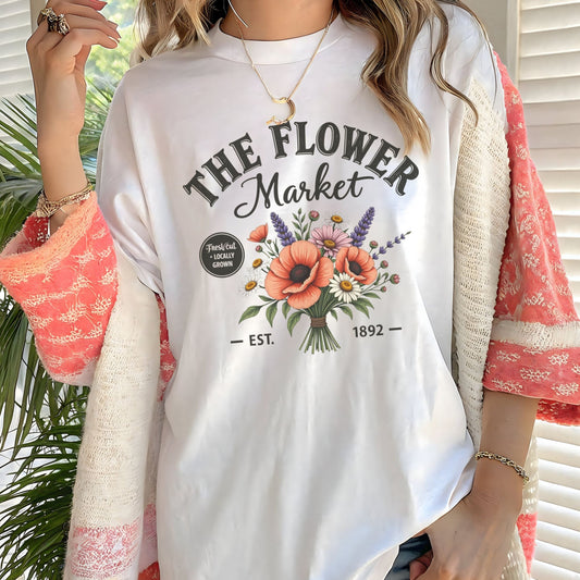 Person wearing a white t-shirt with 'The Flower Market' design and floral elements.