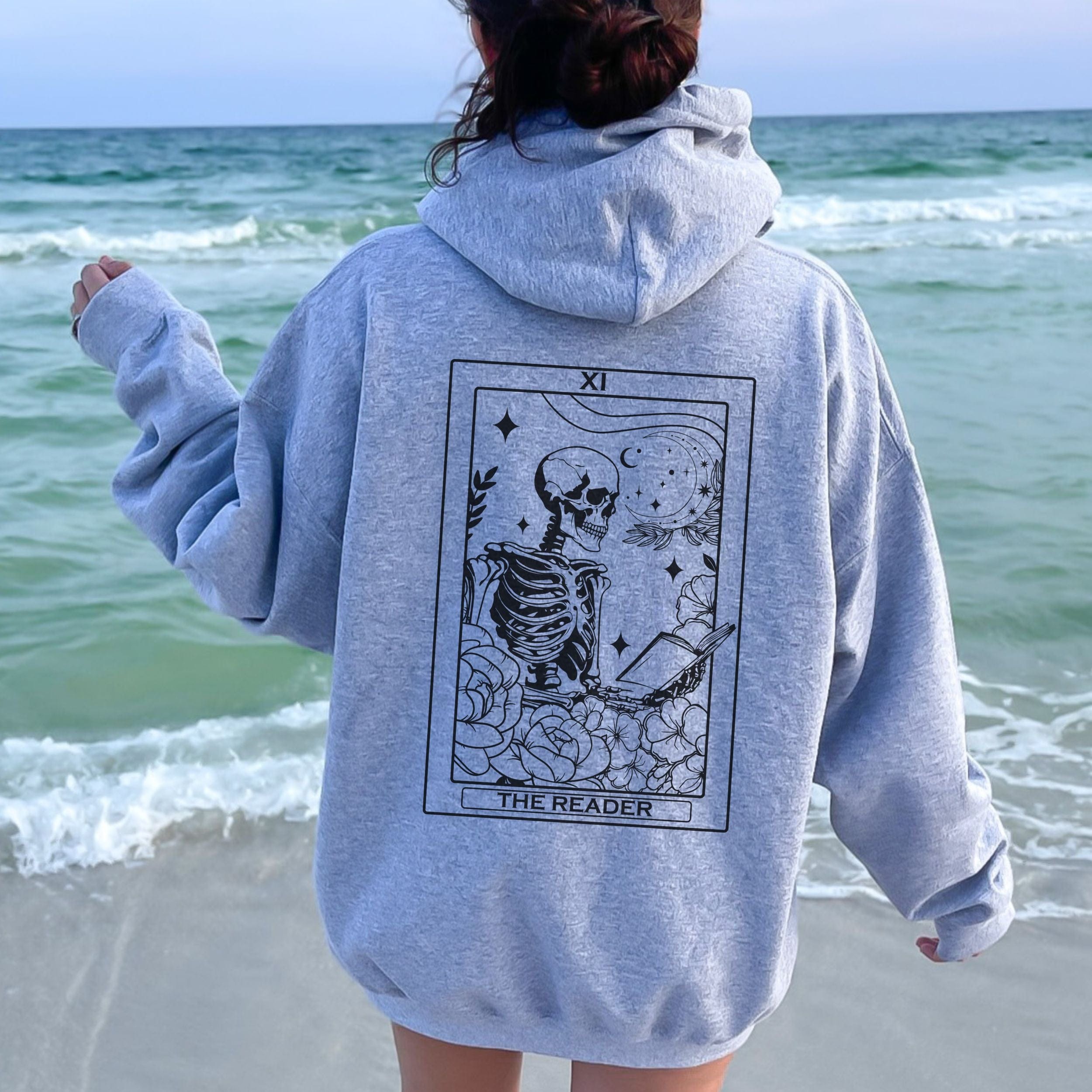 Person wearing a gray hoodie with a skeleton design on the beach