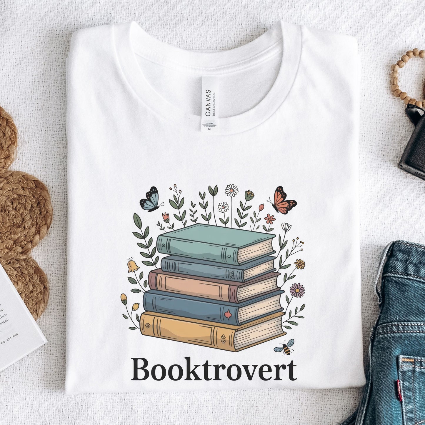 White t-shirt with 'Booktrovert' design featuring books and flowers on a textured surface.