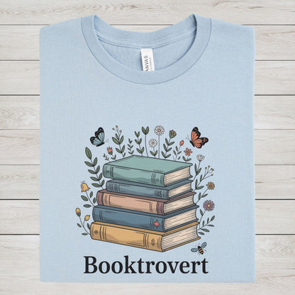 Light blue t-shirt with a graphic of books and flowers on a wooden surface