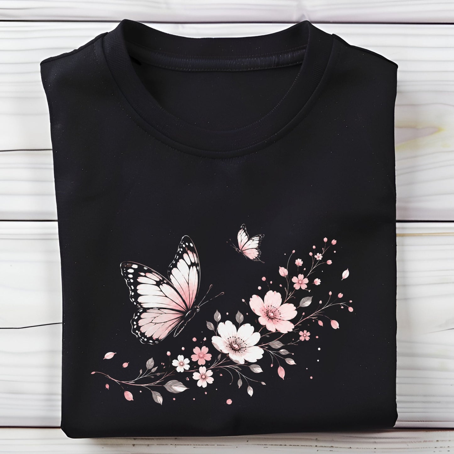 Black t-shirt with pink butterfly and floral design on a wooden surface