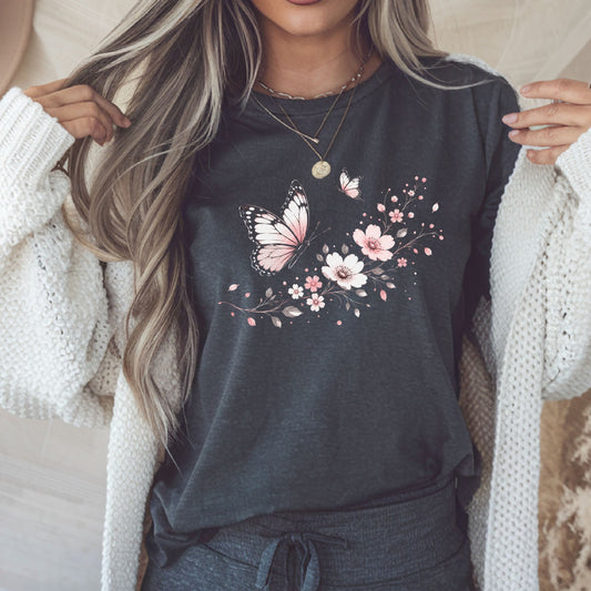 Person wearing a dark gray t-shirt with floral and butterfly design, holding a phone.