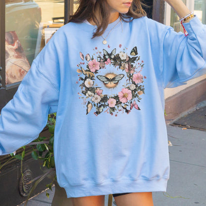 Person wearing a light blue sweatshirt with butterfly and floral design outdoors.