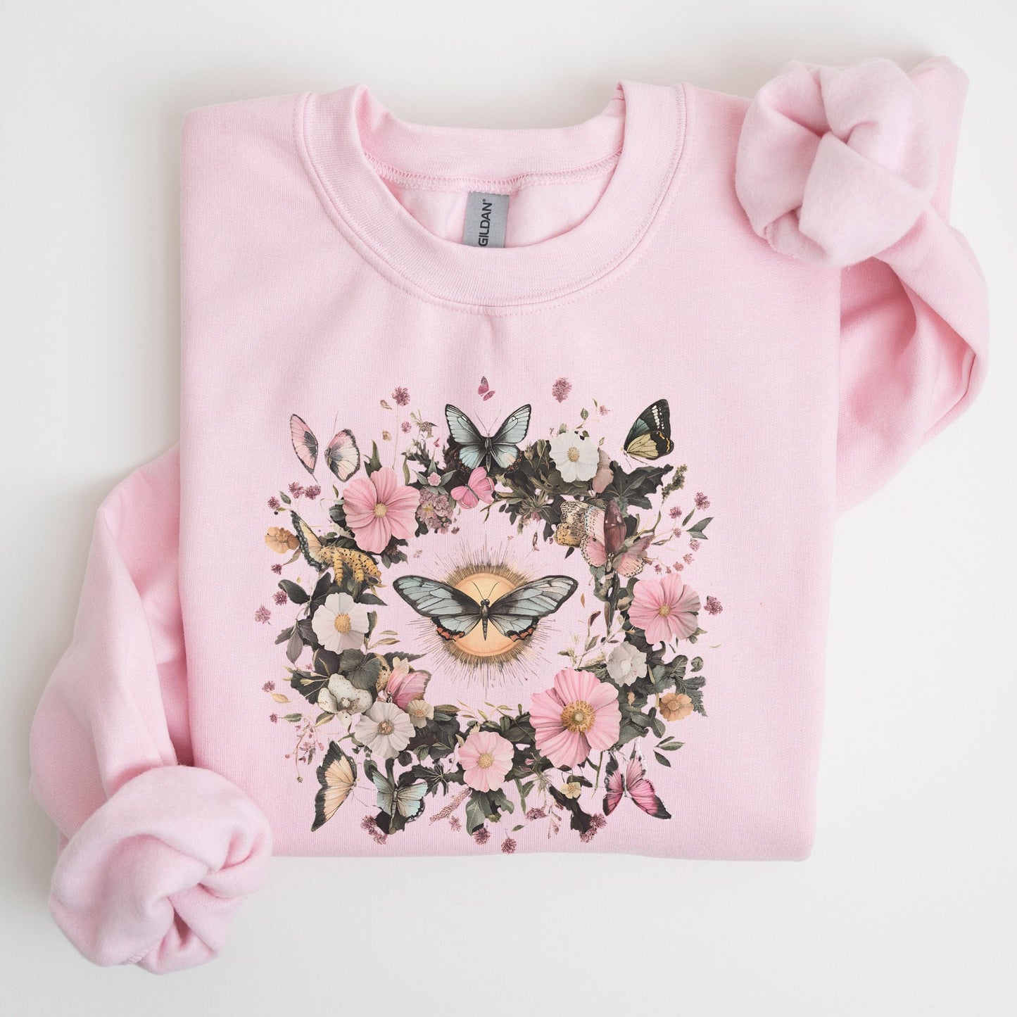 Pink sweatshirt with floral and butterfly design on a light background
