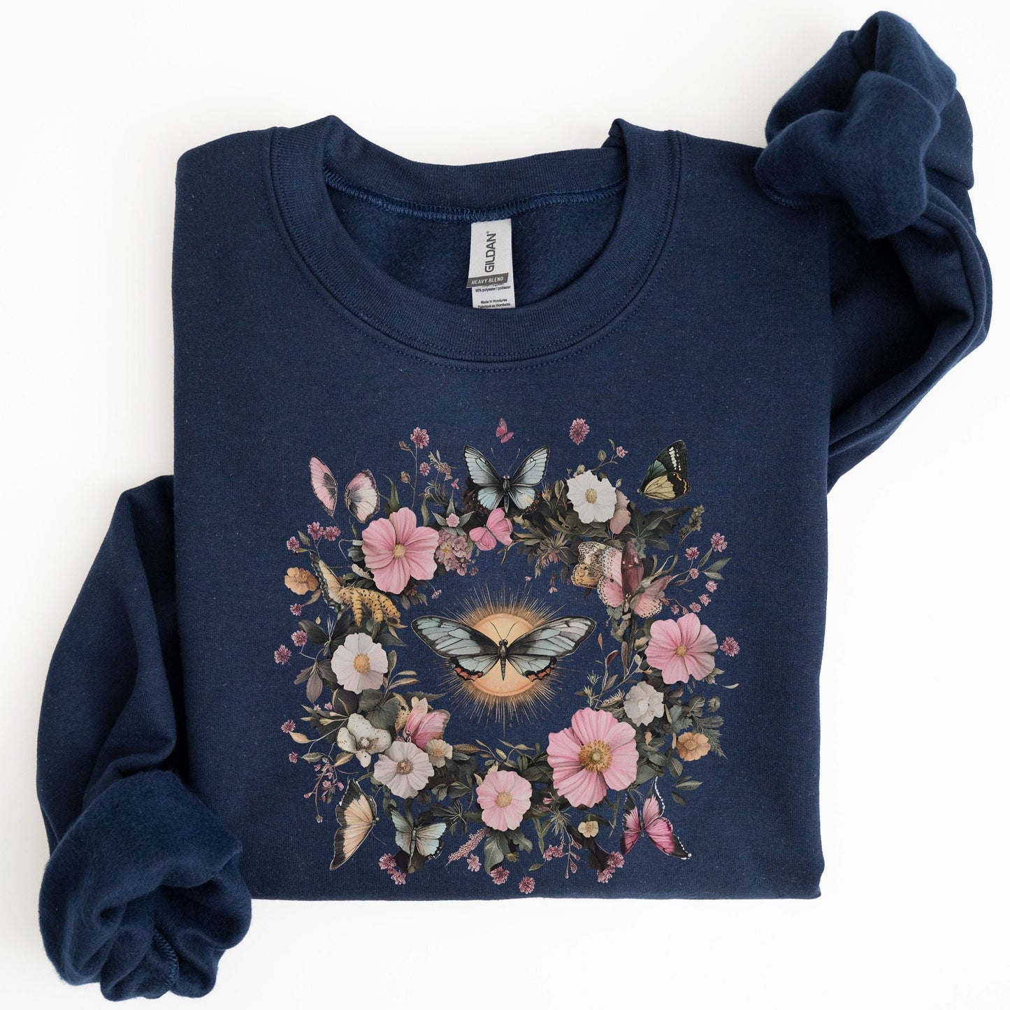 Folded navy blue sweatshirt with floral and butterfly design on a white background