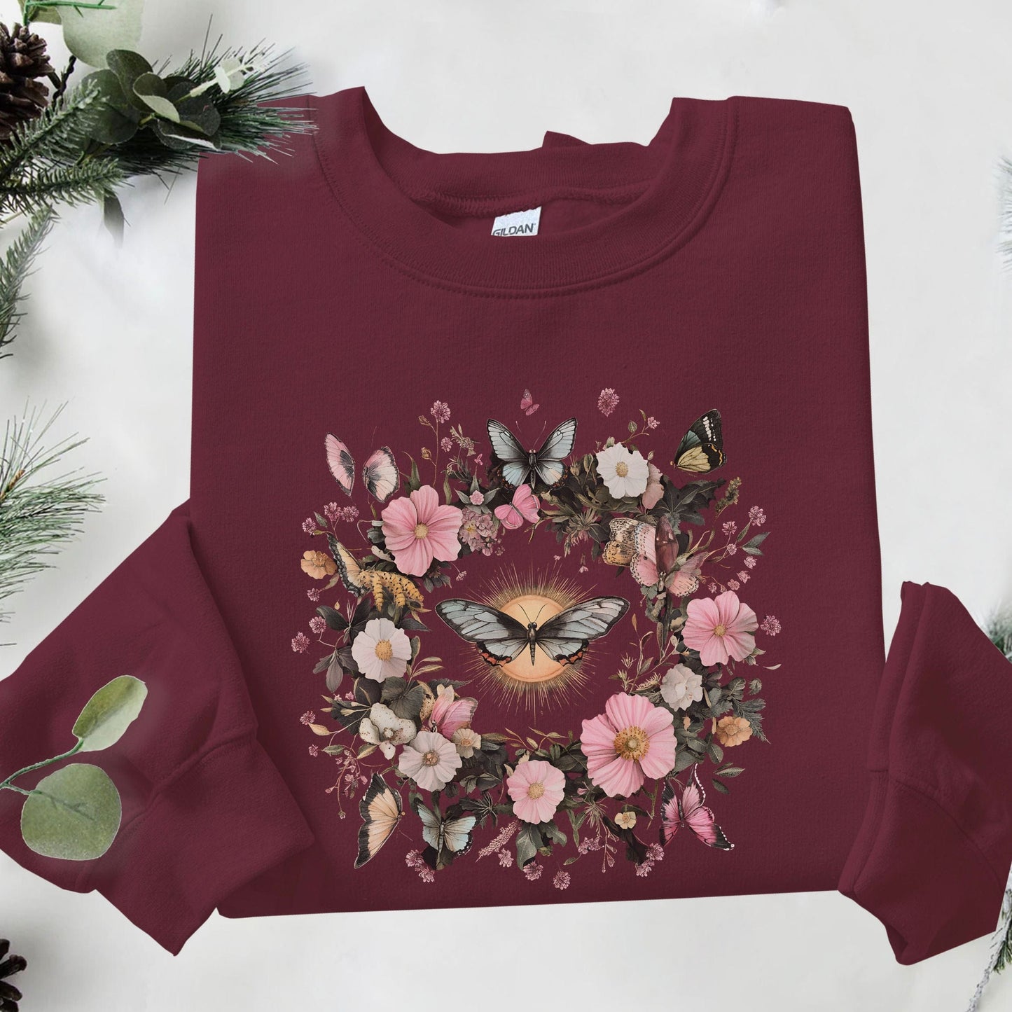 Maroon sweatshirt with floral and butterfly design on a white background