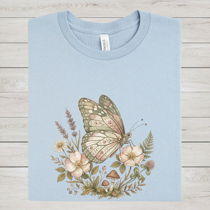 Light blue t-shirt with a butterfly and floral design on a wooden surface