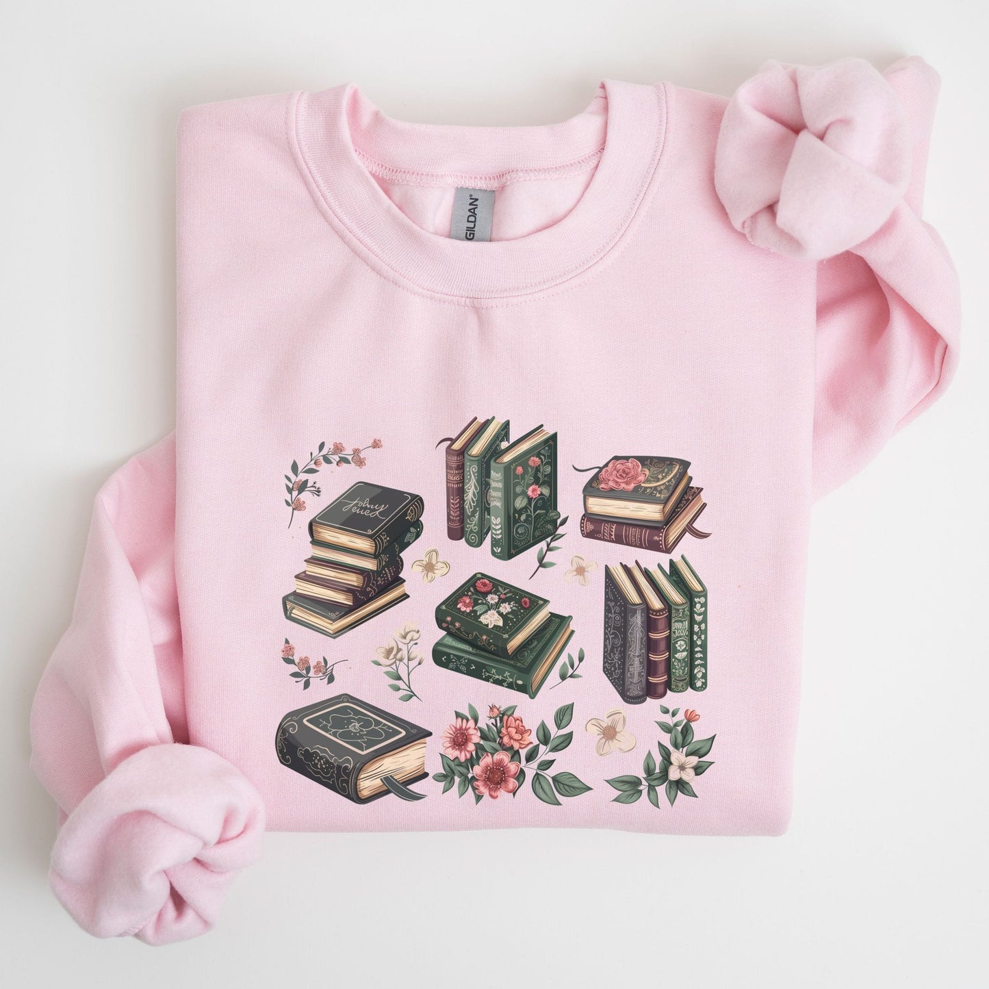 Pink sweatshirt with book and floral design on a light background